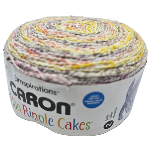 Image of single cake of Caron Cotton Ripple Cakes yarn in the color Mauve Glow with label on a white background.