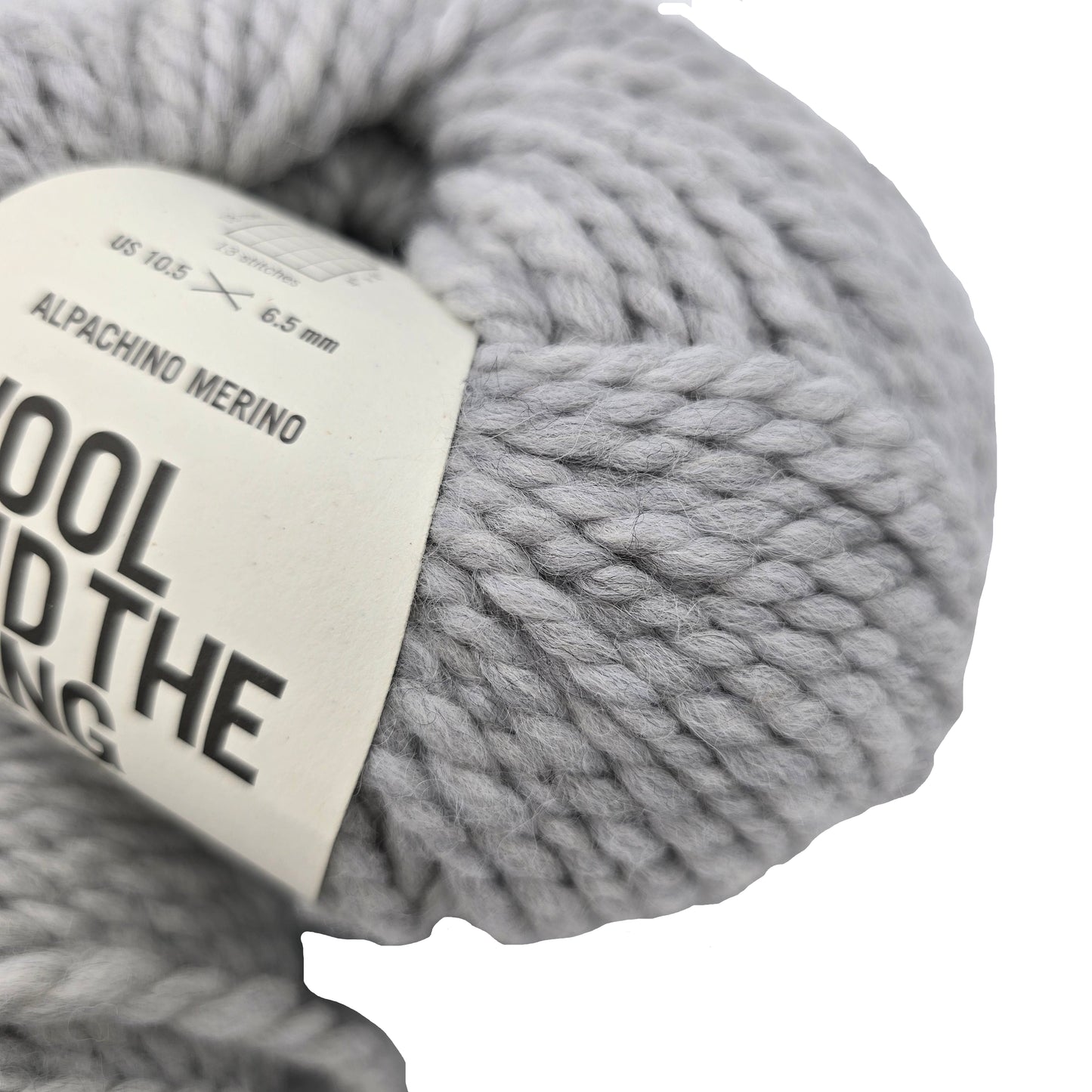 Close-up Alpachino Merino yarn by Wool And The Gang in the color Rocky Grey with partial label on a white background.
