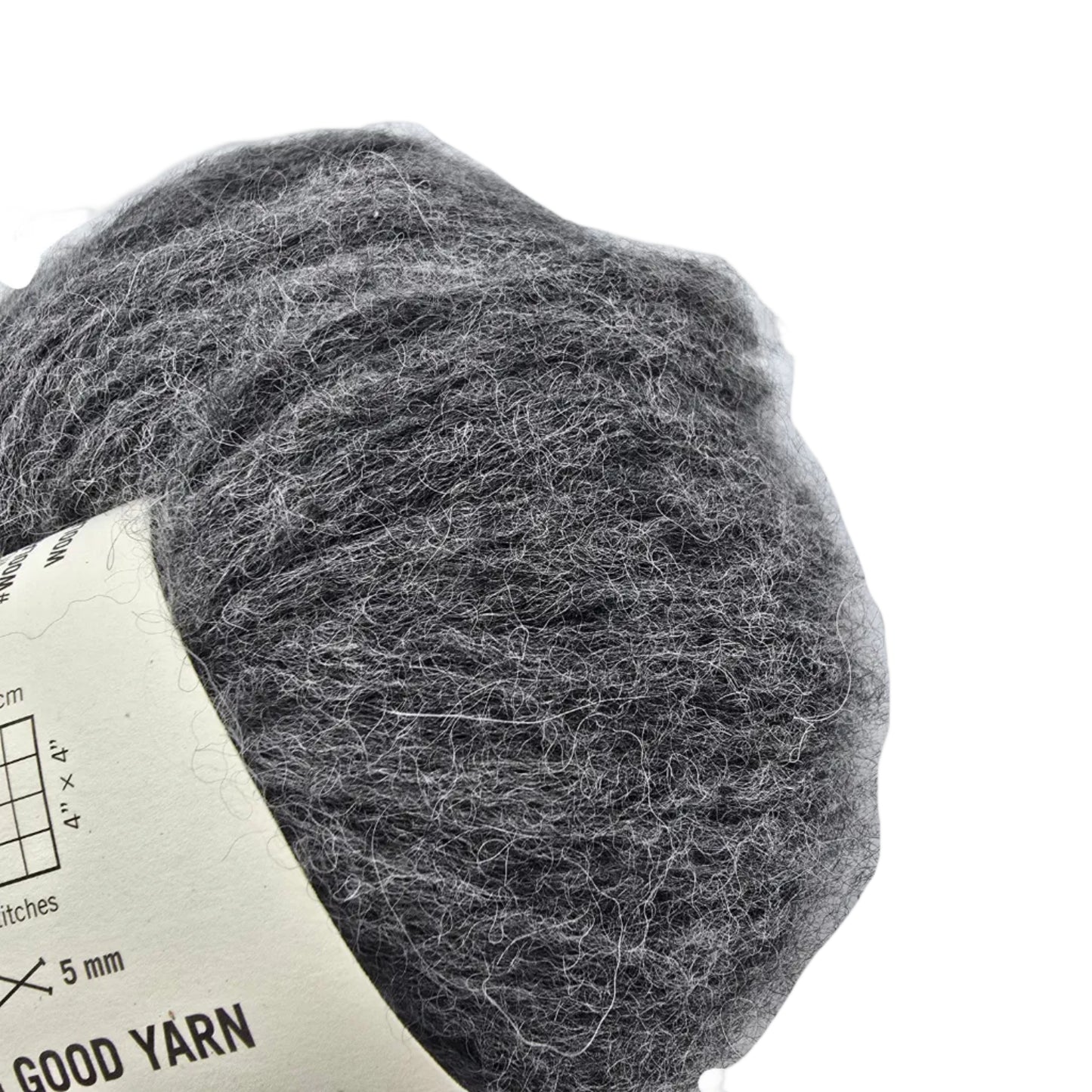 Close-up Image of a single ball of Feeling Good Yarn by Wool And The Gang in the color Silver Fox Grey with partial label visible on a white background.