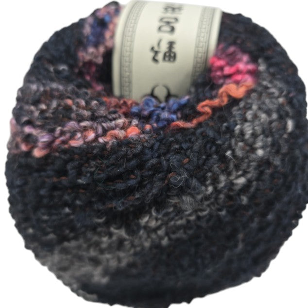 extreme close-up image of a single ball of Kanzashi by Noro Yarn - Color 16 Kasatsu on a white background.