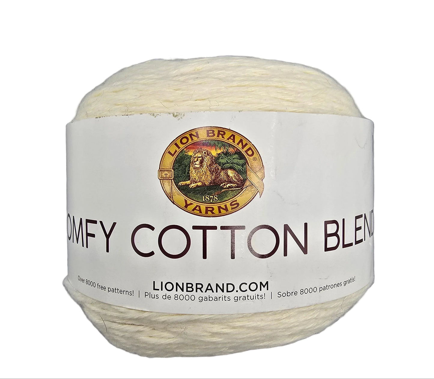 A ball of cream-colored yarn with a white paper label that reads 'COMFY COTTON BLEND' and features the Lion Brand Yarns logo, set against a plain gray background.
