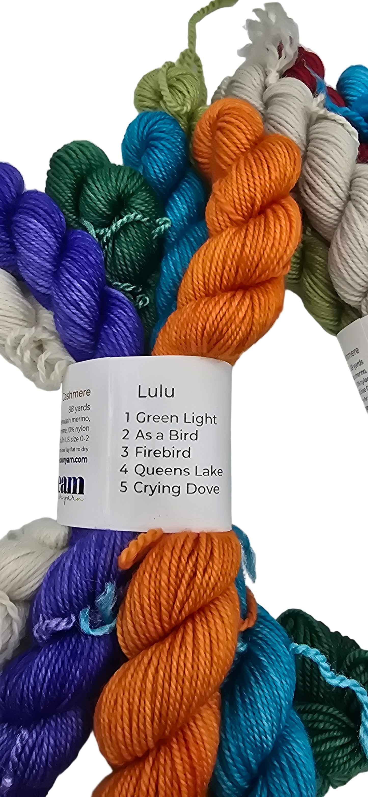 Image of multiple different colored mini skeins of Smooshy Cashmere by Dream yarn in color package named Lulu with label on white background