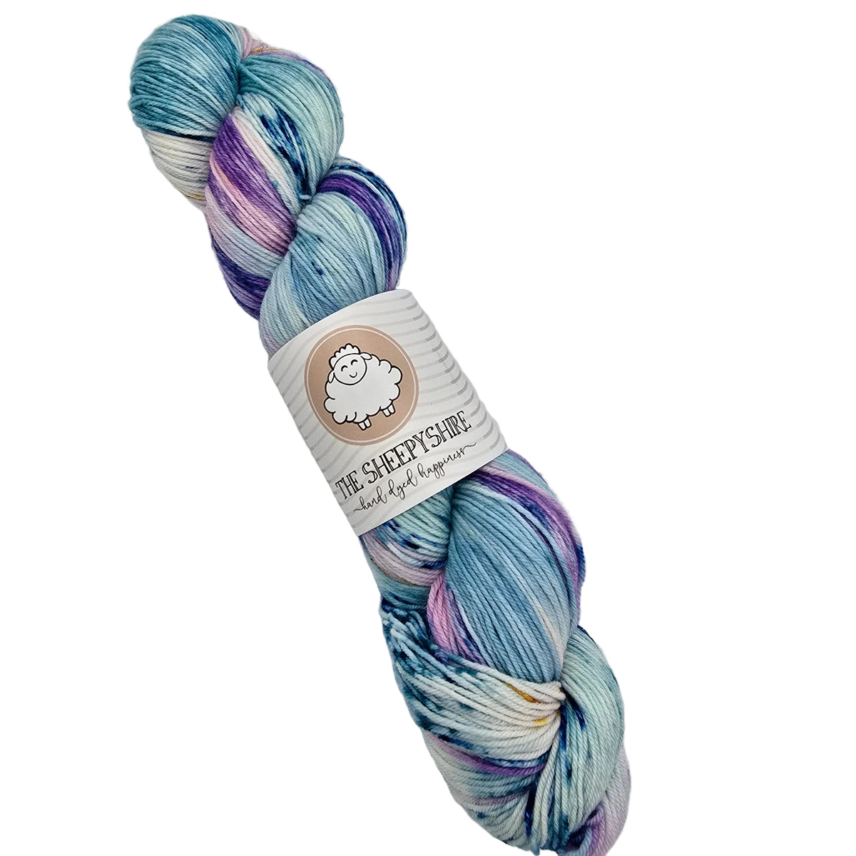 A single skein of variegated yarn with blue, purple, and white marled colors, wrapped in a paper label that reads 'THE SHEEPYSHIRE' on a white background.