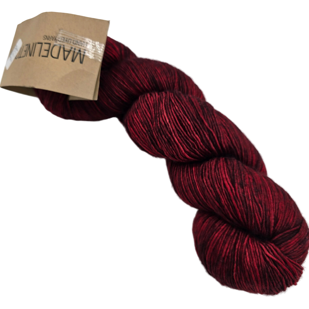 Image of a single hank of Tosh Merino Light yarn by Madelinetosh -in the color Tart with label on a white background.