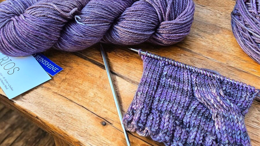 Image of Malabrigo Rios Yarn with completed swatch on wooden background with Chiaogoo size 6 needles