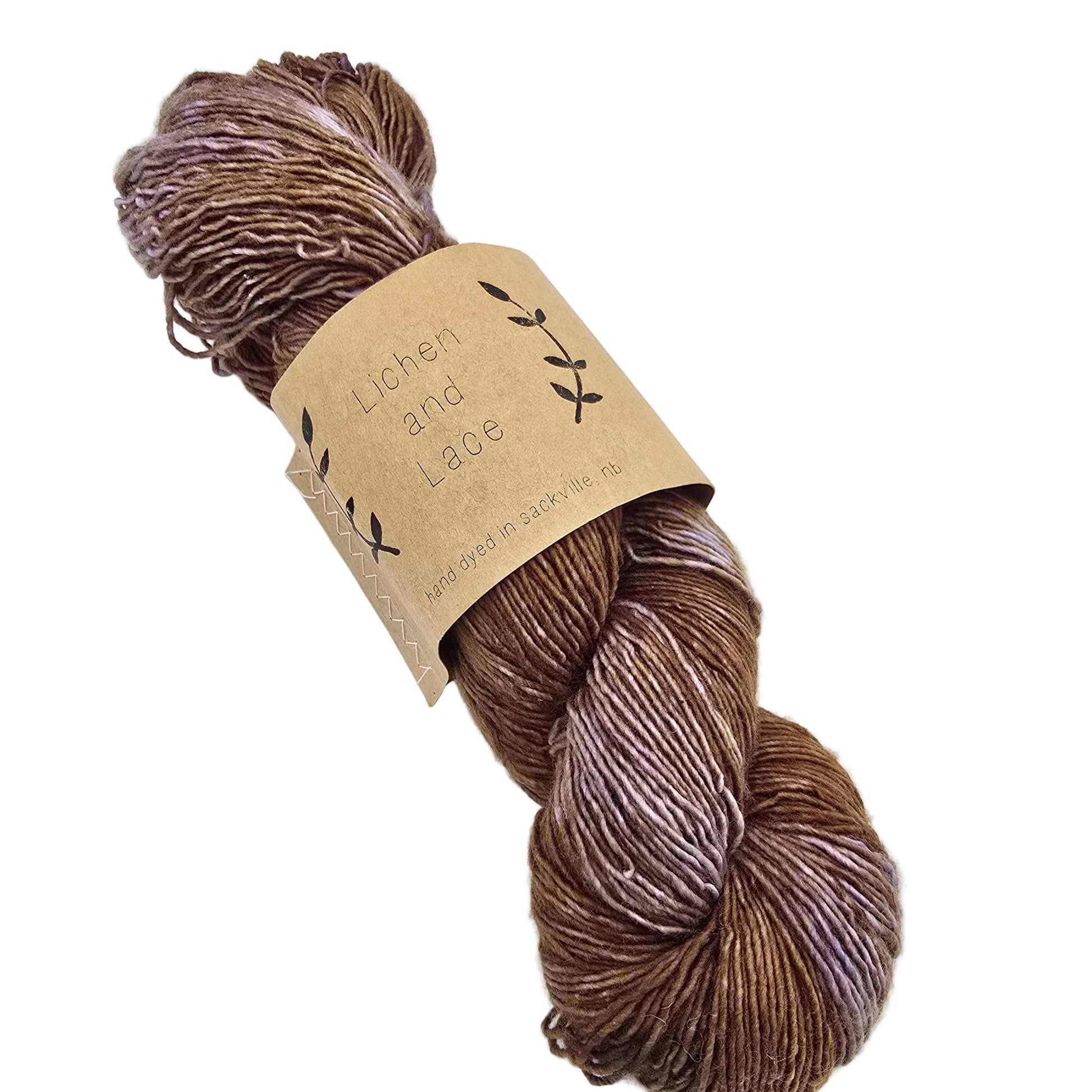 A skein of 1 ply SW Merino Fingering by Lichen and Lace in the color sweet potato a variegated brown colorway, wrapped in a kraft paper label, on a clean white background.