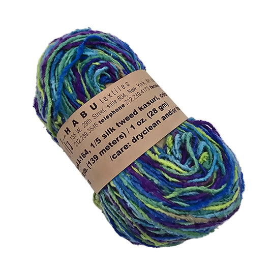 Image of a single hank of A-164 1/5 Silk Tweed Kasuri Yarn by Habu Textiles in the Color L9 with label on a white background.