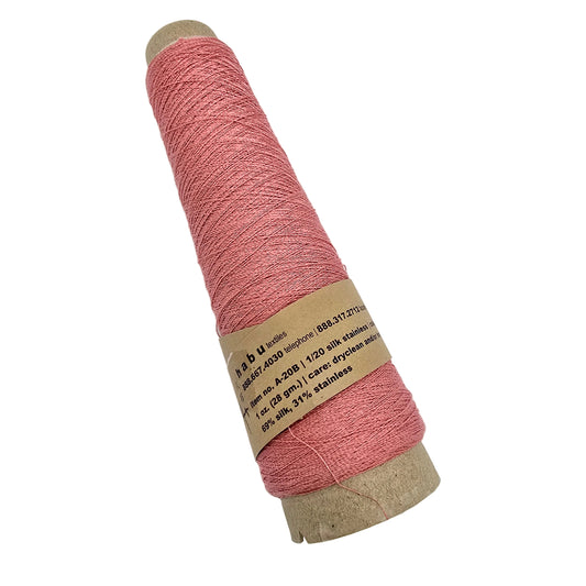 A spool of  pink yarn wound on a cardboard core, with a paper label wrapped around the middle, photographed on a plain white background.