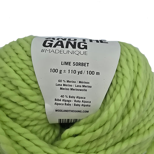 Close-up image a single ball of Alpachino Merino Yarn by Wool And The Gang in the color Lime Sorbet with label on a white background.