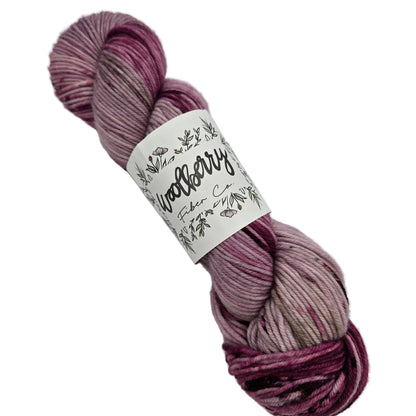 Image of a single skein of Berry DK yarn by Woolberry in the color Galentines Day with label on a white background.