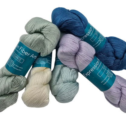 Five skeins of yarn in muted blue, sage green, cream, light blue, and lavender purple, arranged on a white background. Each skein has a teal paper label that reads 'Expression' and 'Yarn Fiber Arts'.