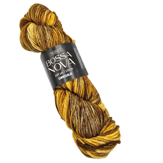 A skein of Círculo yarn from their Bossa Nova collection, featuring a variegated color pattern of golden yellow, mustard, and dark brown. The yarn is wrapped in a black paper label with white text.