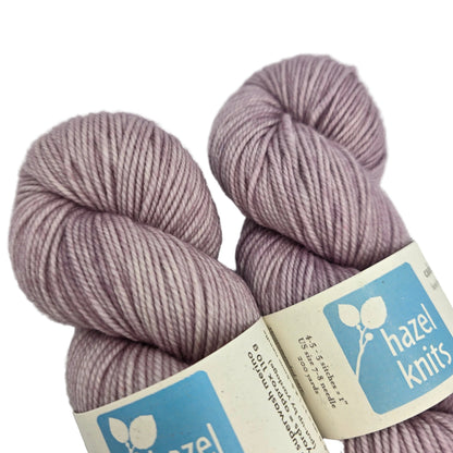 Close-up image of Cadence_yarn by_Hazel_Knits_in the color Thistle with labels on a white background.