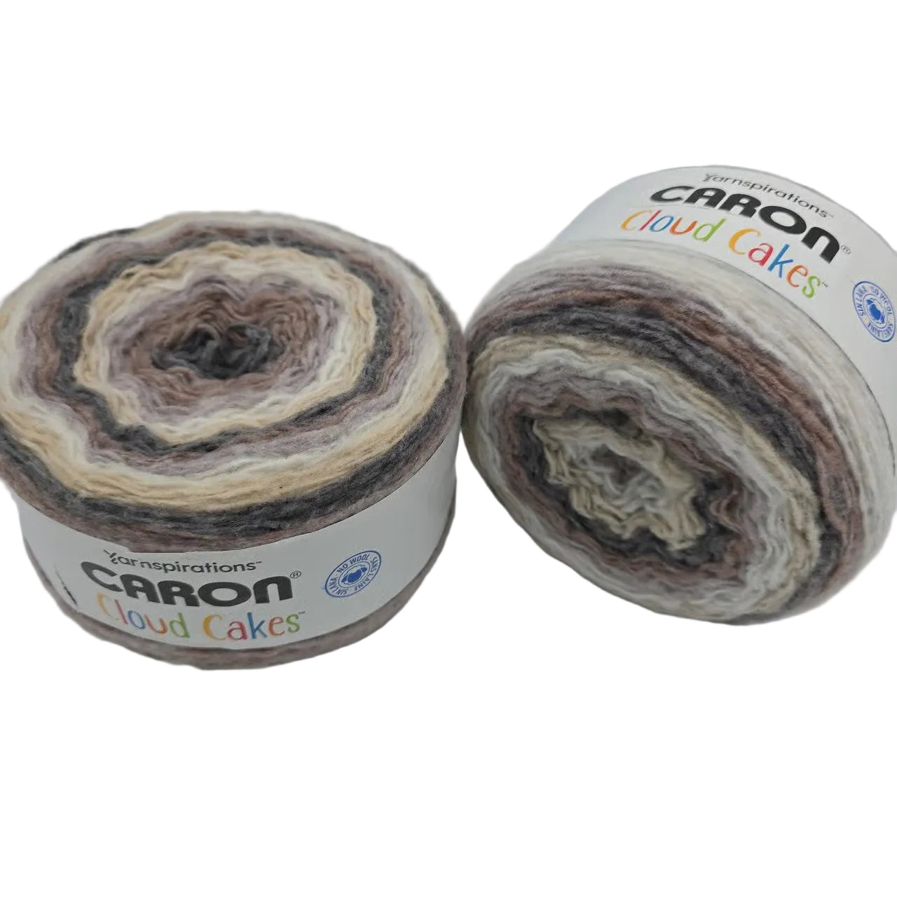 Image of two cakes of Caron Cloud Cakes yarn in the color sandbar with bales on a white background.