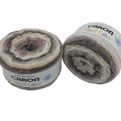 Image of two cakes of Caron Cloud Cakes yarn in the color sandbar with bales on a white background.