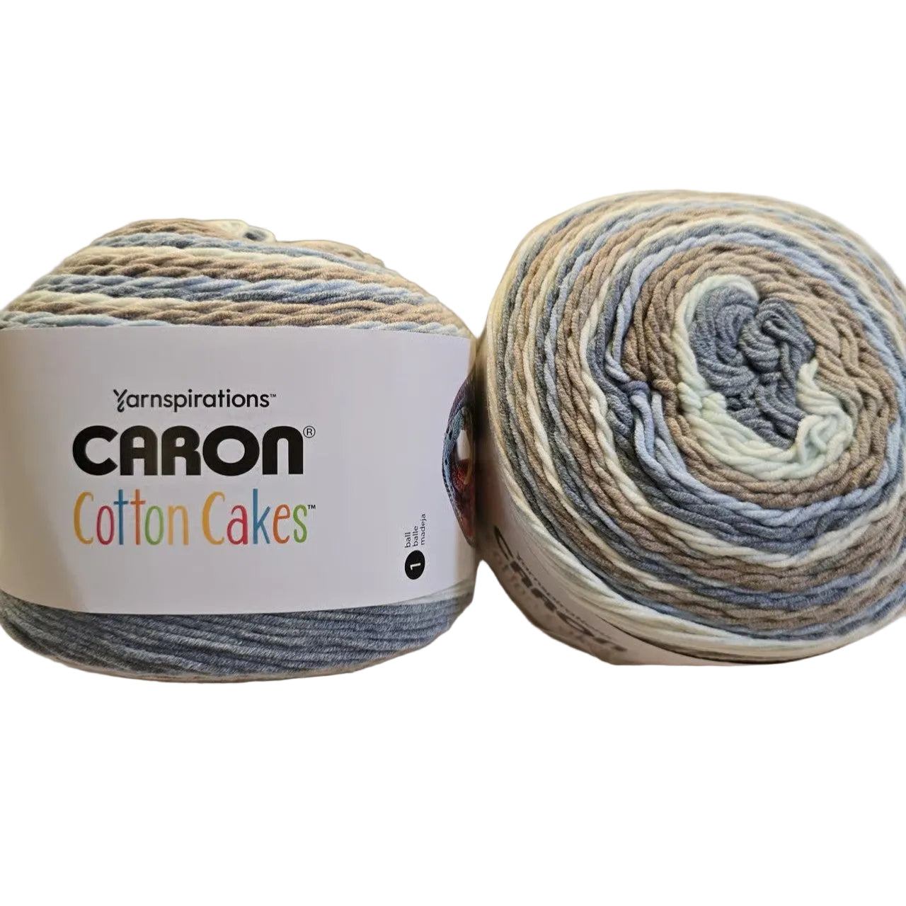 Image of two cakes of Caron Cotton Cakes yarn in the color Nested Blues with label on white background.