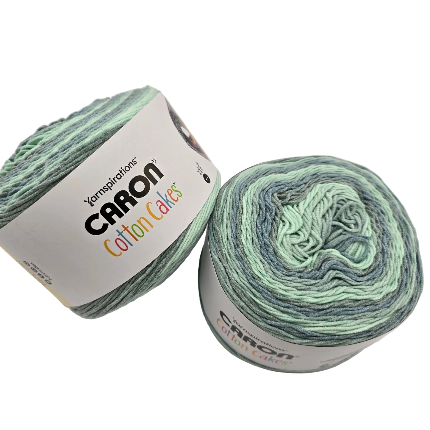 Image of two cakes of Caron Cotton Cakes Yarn in the color High Tide with labels on a white background.