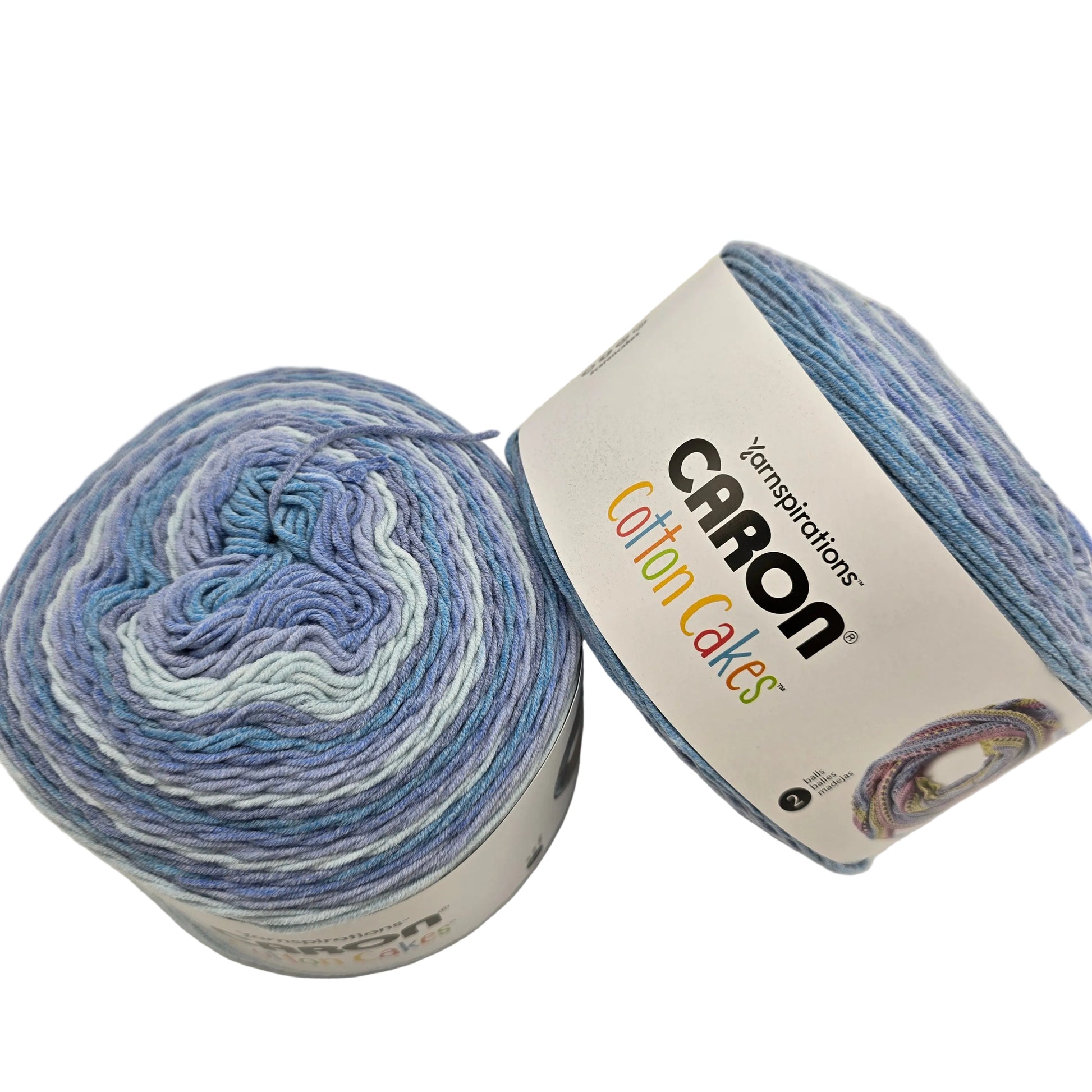 Image of two cakes of Caron Cotton Cakes Yarn in the color Wild Blueberry with labels on a white background.