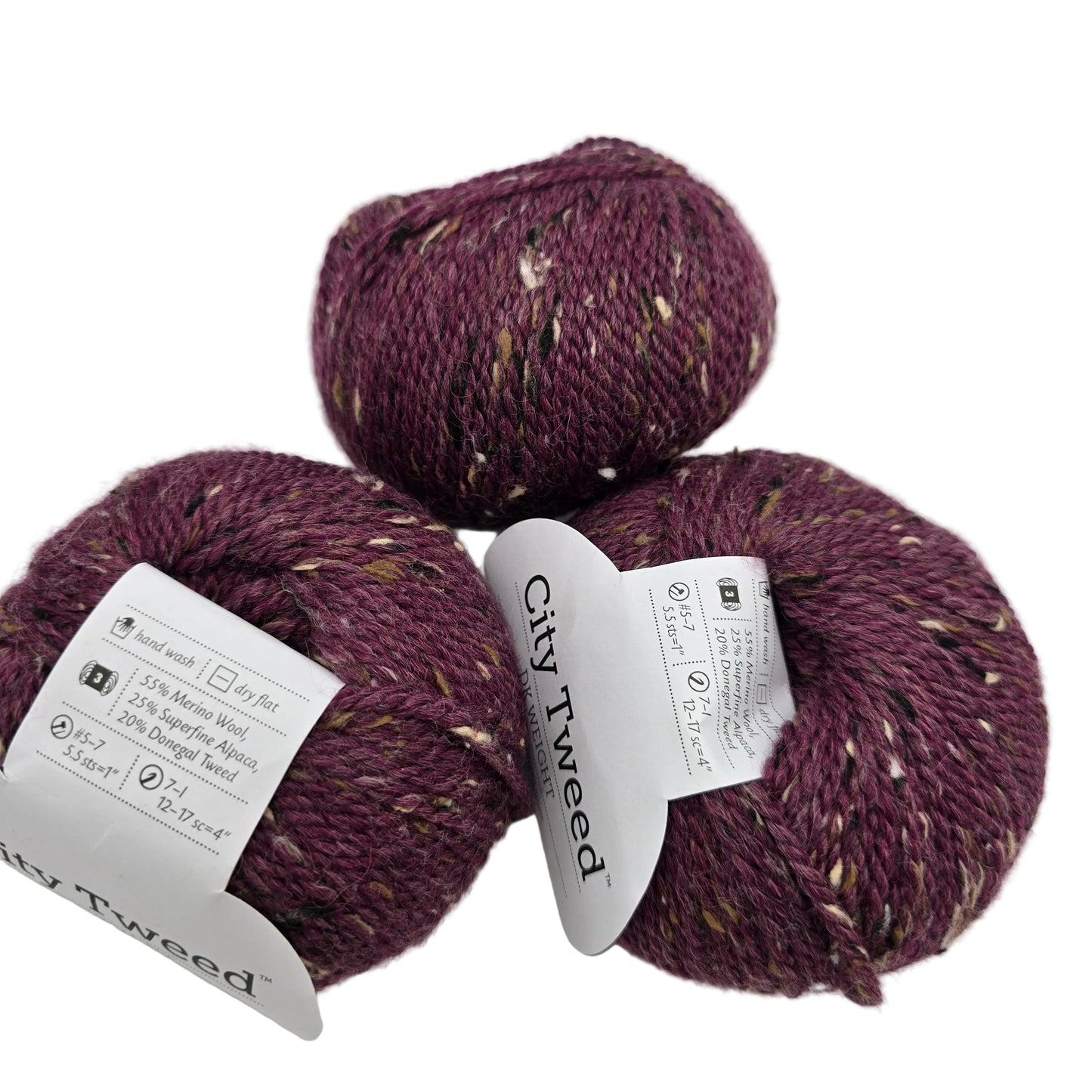 Image of three balls of City Tweed DK by Knit Picks yarn in the color Plum Wine with labels on a white background.