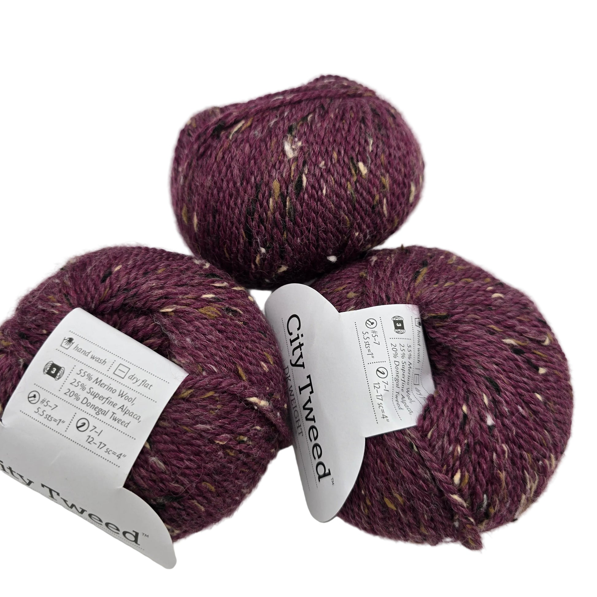 Image of three balls of City Tweed DK by Knit Picks yarn in the color Plum Wine with labels on a white background.