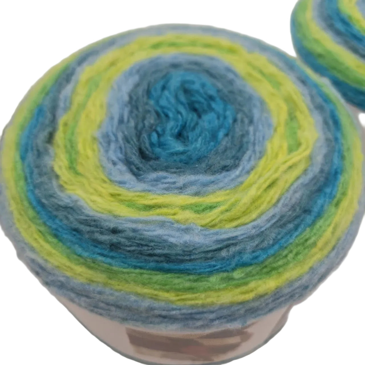 Close-up overhead image of a single cake of Caron Cloud Cakes Yarn in the color Tidal Wave  on white background.