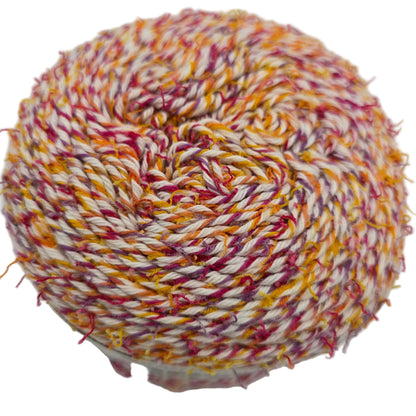 Close-up image of a single cake of Caron Coconut Cakes yarn in the color Tutti Frutti on a white background.