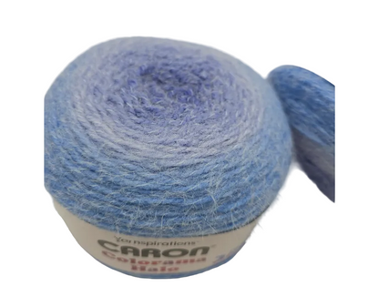 Close-up image of Caron Colorama Halo Perfect Phasing  Yarn Cakes in the color Ultra Marine with label on a white background.