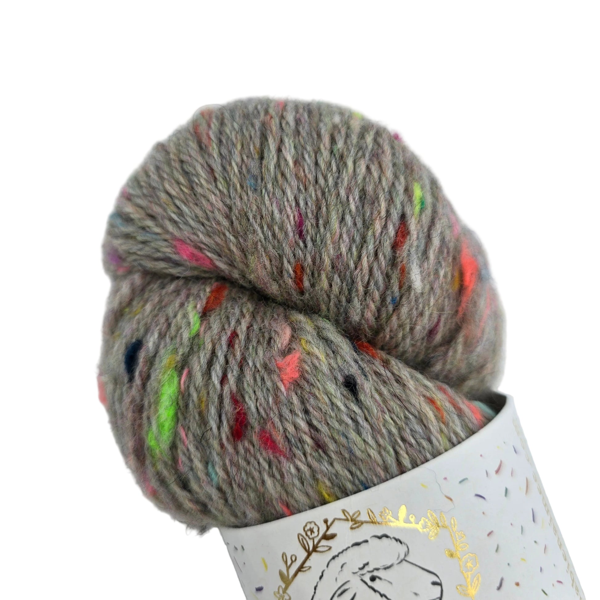 A skein of Corrie_Confetti_by_La_Bien_Aimee_in the color_Greybow_2_Fall_Winter_2021 variegated yarn in a heathered taupe-gray color with colorful flecks, partially wound on a white paper cone with a gold foil sheep outline.