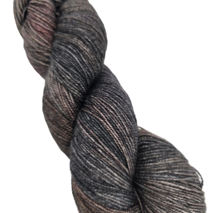 Close-up image of a singel skein of Hawthorne Fingering Weight Yarn by Knit Picks in the color Rockaway Hand painted on a white background.