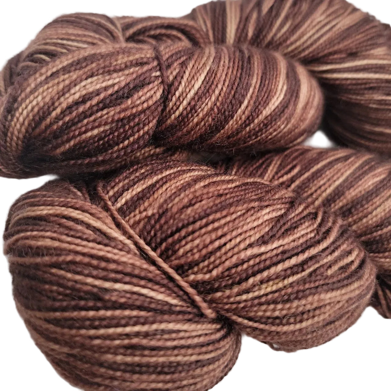 Close-up Image of two skeins of Knit Picks Hawthorn Fingering Yarn in the color Faun Kettle Dye on a white background.