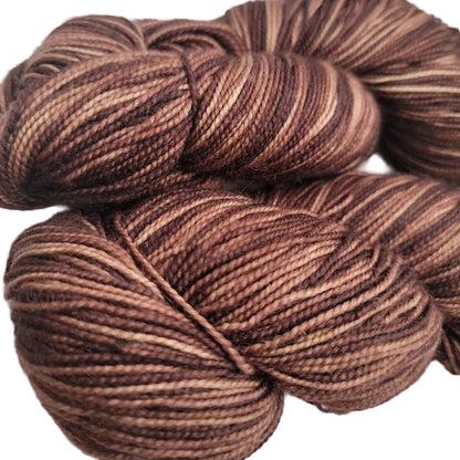 Close-up Image of two skeins of Knit Picks Hawthorn Fingering Yarn in the color Faun Kettle Dye on a white background.