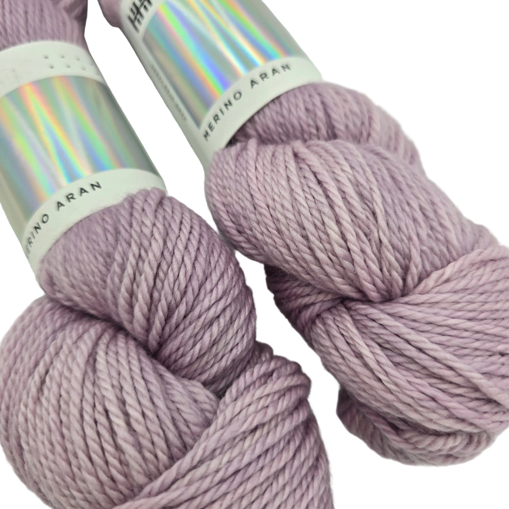 Close-up image of the two skeins of Merino Aran Yarn by Hedgehog Fibres in the color Ghost with labels on a white background.