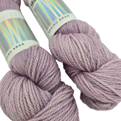 Close-up image of the two skeins of Merino Aran Yarn by Hedgehog Fibres in the color Ghost with labels on a white background.