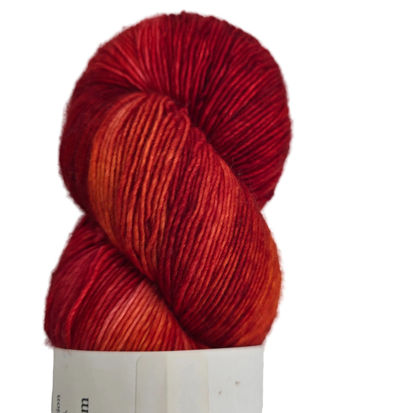 Close-up image of Merino_Singles_Yarn by_La_Biene_Aimee_in the color Calcifer with partial label on a white background.