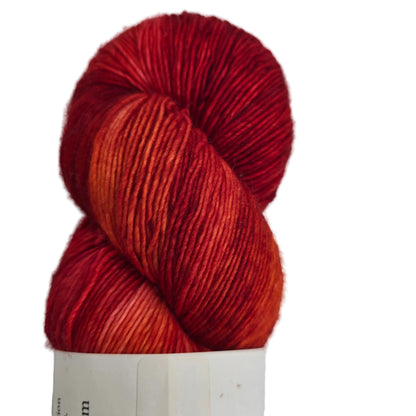 Close-up image of Merino_Singles_Yarn by_La_Biene_Aimee_in the color Calcifer with partial label on a white background.