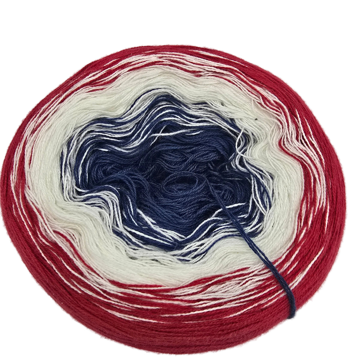 A circular cake of variegated yarn with concentric rings of dark navy blue, off-white, and bright red, photographed on a plain white background.