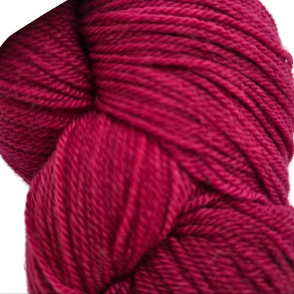 Close-up image of Organic Merino Yarn by Swans Island in the color Garnet YF101 on white background.