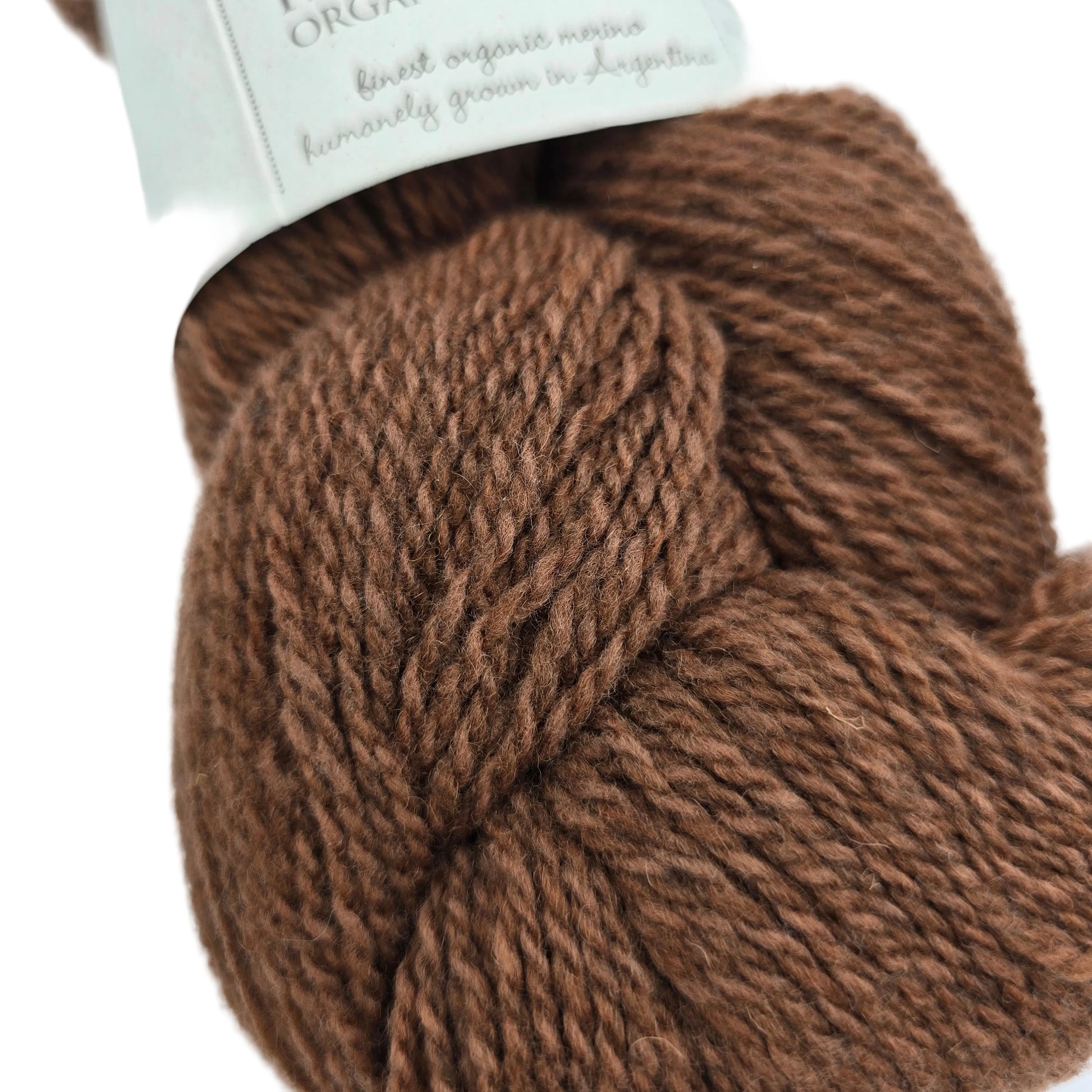 Close-up image of Patagonia Organic Merino Wool Yarn  by Juniper Moon Farm in the color Sequoia with partial label on a white background.