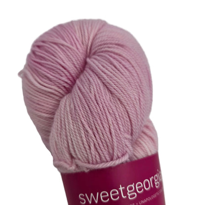 Close-up image of Tough Love Sock by SweetGeorgia Yarns  in the color Candy Floss with partial label on a white background.