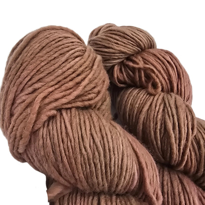 Close-up Image of two skeins of Worsted by Malabrigo Yarn in color 158 Cognac on a white background.