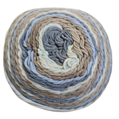 Close-up image of a single cake of Caron Cotton Cakes yarn in the color Nested Blues on a white background.