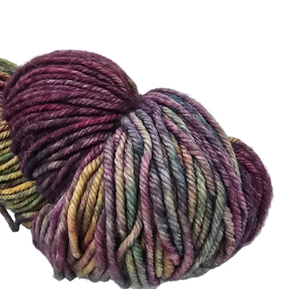 Close-up Image of a single skein of Rios by Malabrigo Yarn in the color 886 Diana which is a purple heavy multicolor with label in a white background.