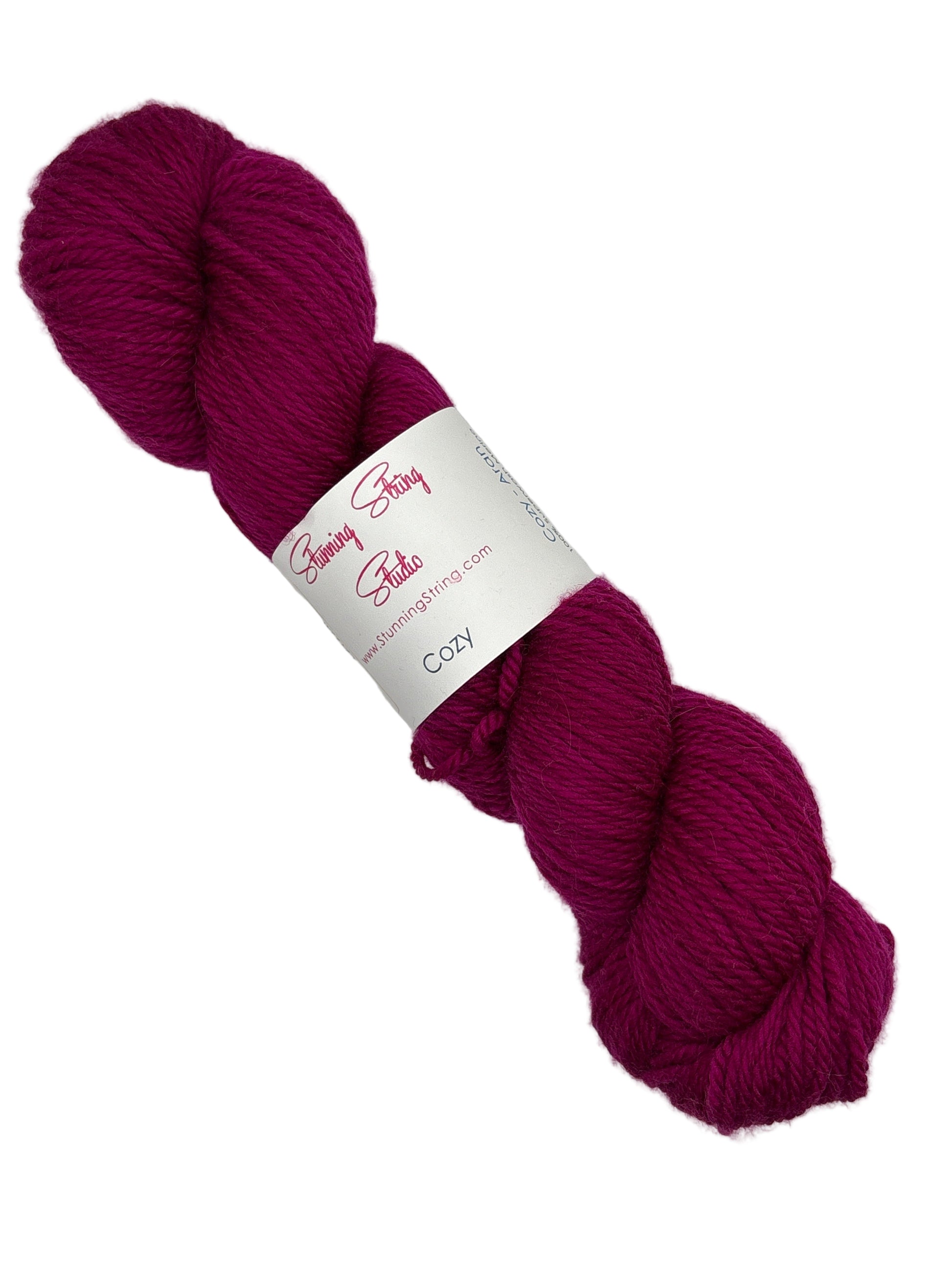 Single skien of Cozy by Stunning String Studio Aran Merino Wool Yarn Skein with label on a white background.