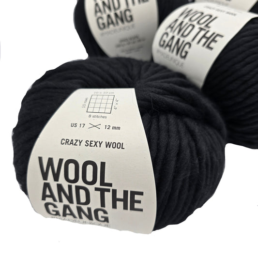 Image of several balls of Crazy Sexy Wool yarn by Wool And The Gang in the color Space Black with labels on a white  background.