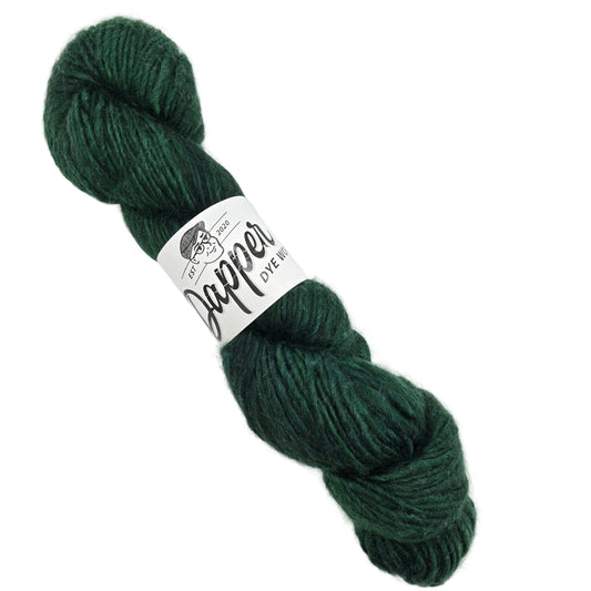 Image of a single skein of Crooner yarn  by Dapper Dye Works in the color Purdy with label on a white background.