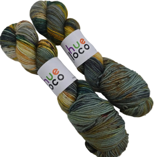 Image of two skeins of DK by Hue Loco Yarn in the color Serama Rooster with label on a white background.