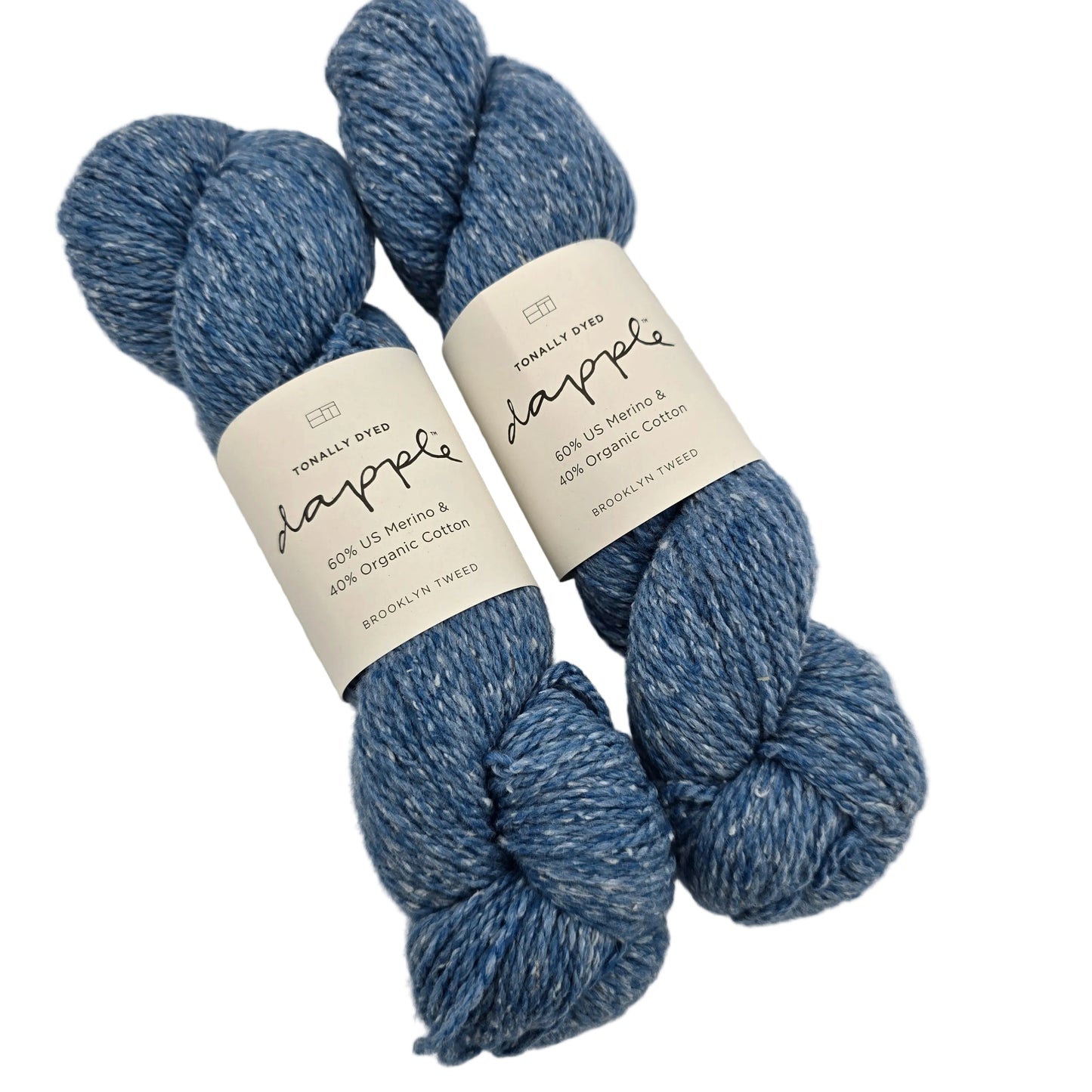 Image of two skeins of Dapply by Brooklyn Tweed Yarn in the color Blueprint with labels on a white background.