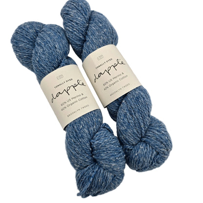 Image of two skeins of Dapply by Brooklyn Tweed Yarn in the color Blueprint with labels on a white background.