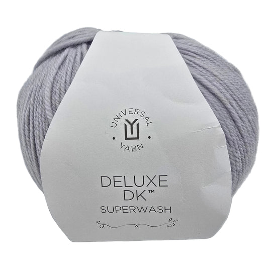 A ball of  Deluxe DK Superwash yarn in the color Ice Rustic a light lavender-gray colorway, wrapped in a white paper label.