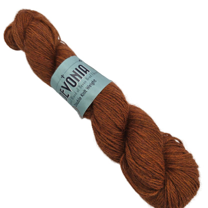 Image of a single skein of Devonia DK yarn by John Arbon Textiles  in the color Amber Blaze with label on a white background.